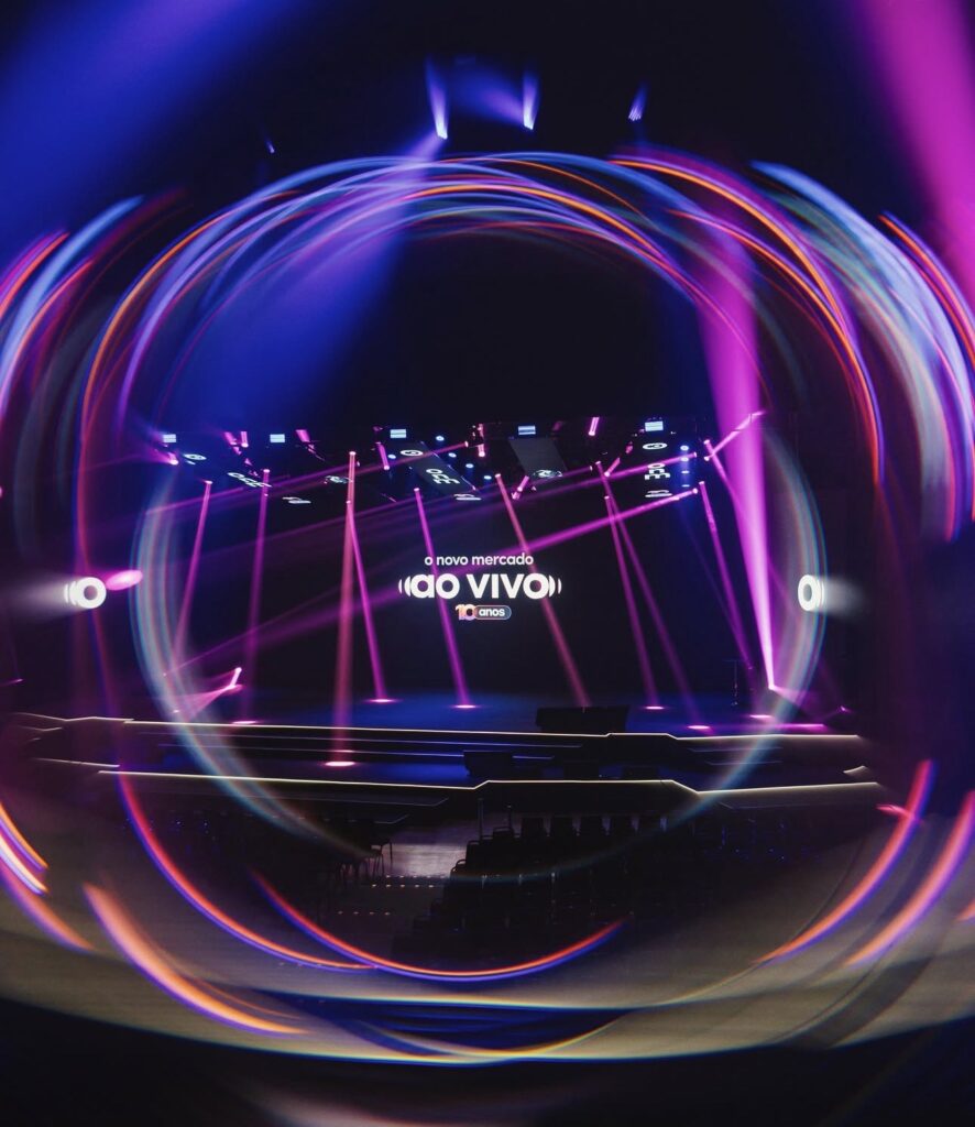 Palco do evento O Novo Mercado ao Vivo, edição de 10 anos, com iluminação em tons de roxo e rosa